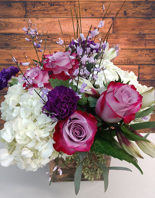 “Magical Moments”<br />
A magical arrangement of hydrangeas, roses, carnations and fillers in a cube or round vase in a compact design. (Color of roses may vary) $60 – $70.